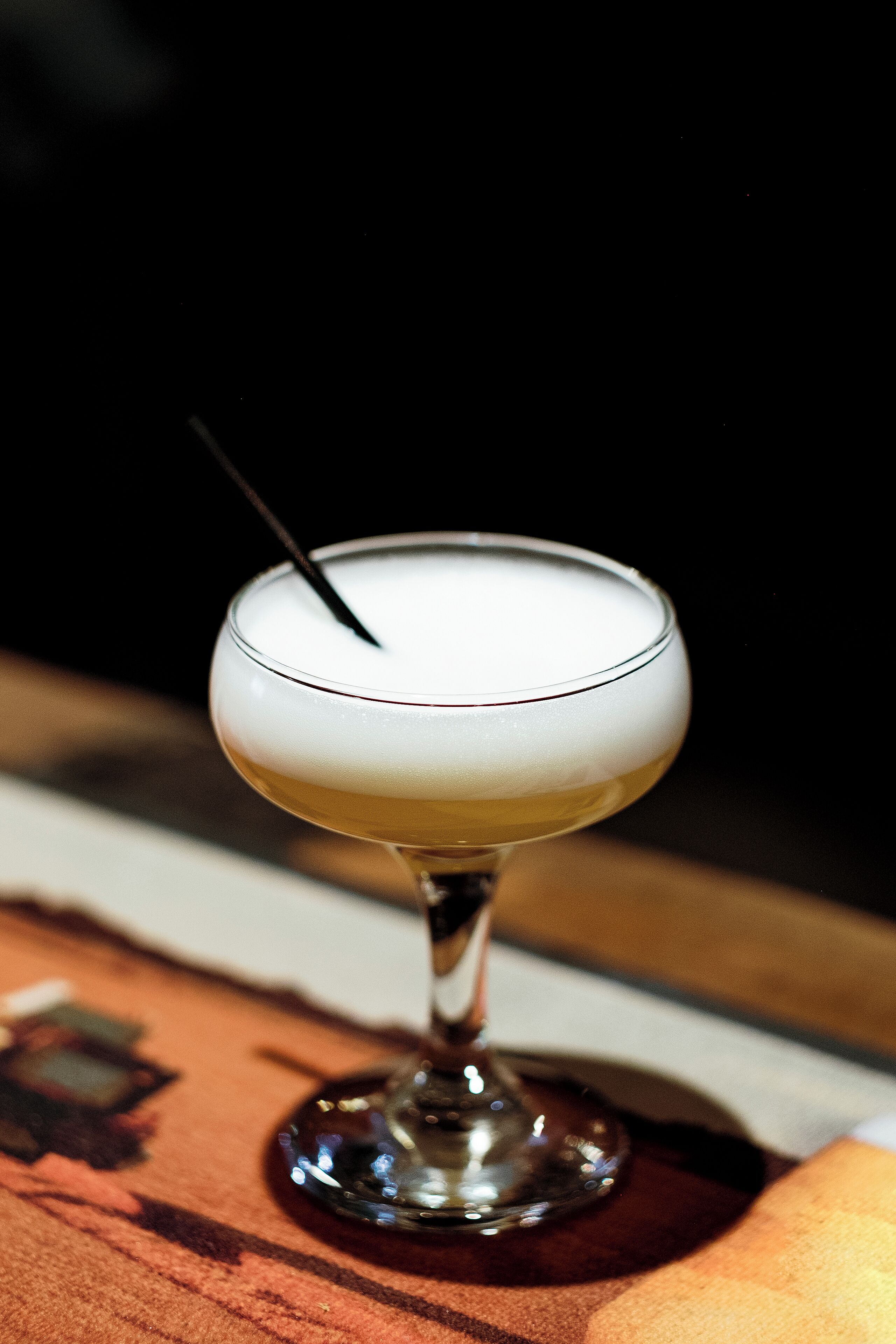 A cocktail glass with a straw on a table.