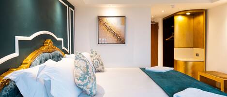 A hotel room with a large bed, a headboard, a bedside table, a nightstand, a wardrobe, and a wall-mounted artwork.
