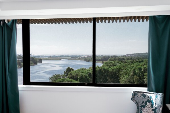 A room with a large window overlooking a river and greenery.