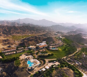 An aerial view of a resort with multiple buildings, a swimming pool, and landscaped areas. - JA Hatta Fort Hotel (Hatta)