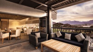 Un espace extérieur aménagé en terrasse, avec des meubles en osier, une table en bois et une vue sur les montagnes.