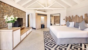 Une chambre spacieuse avec un grand lit, un mur d’accent en pierre, une tête de lit en bois et un design moderne au plafond.