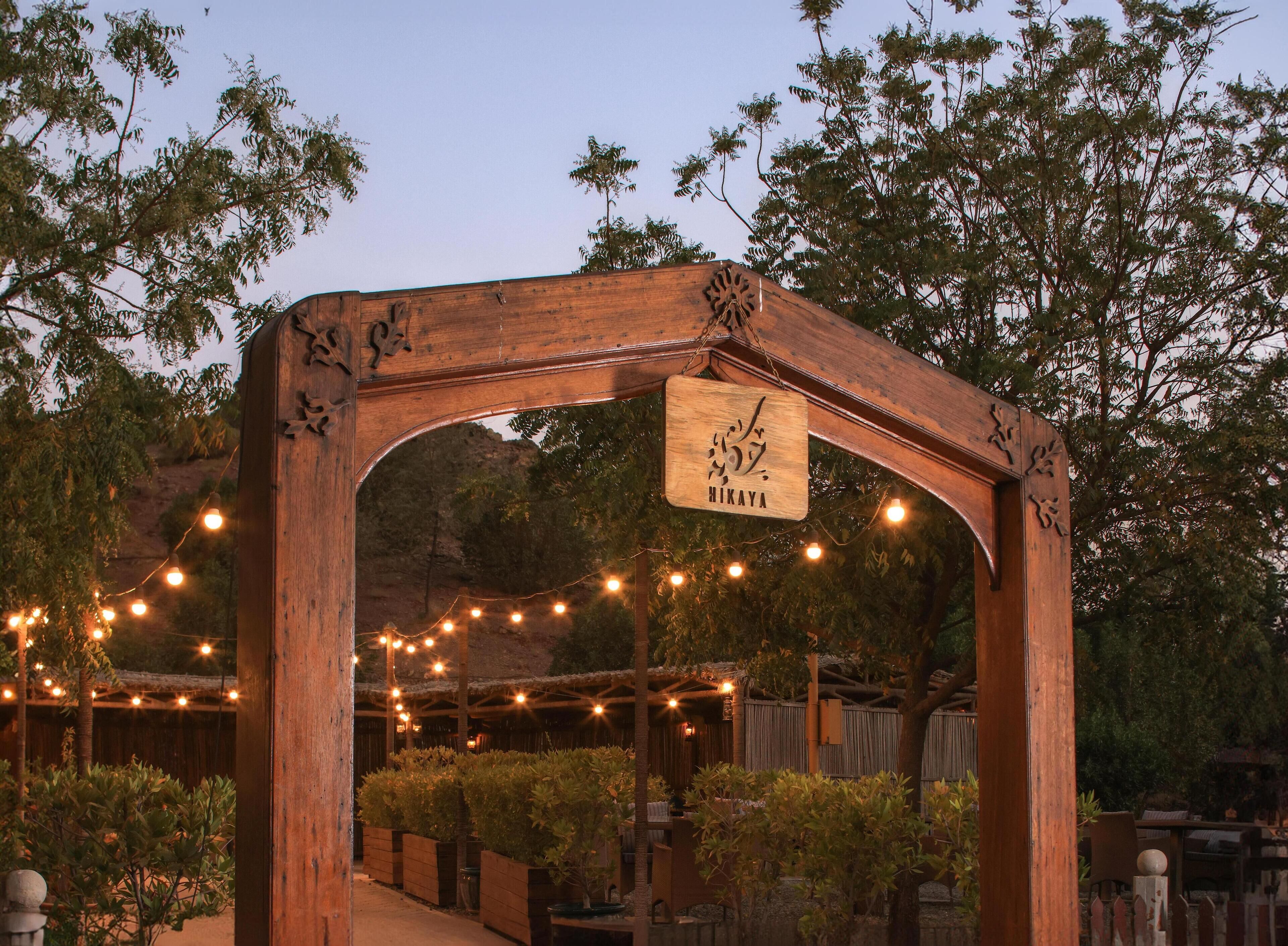 A wooden pergola with a hanging sign that reads "HIKAYA".