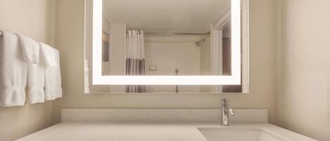 A bathroom with a large mirror, a sink, and a towel rack.