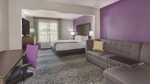 Une chambre d’hôtel avec un lit, un canapé, un bureau et une télévision.