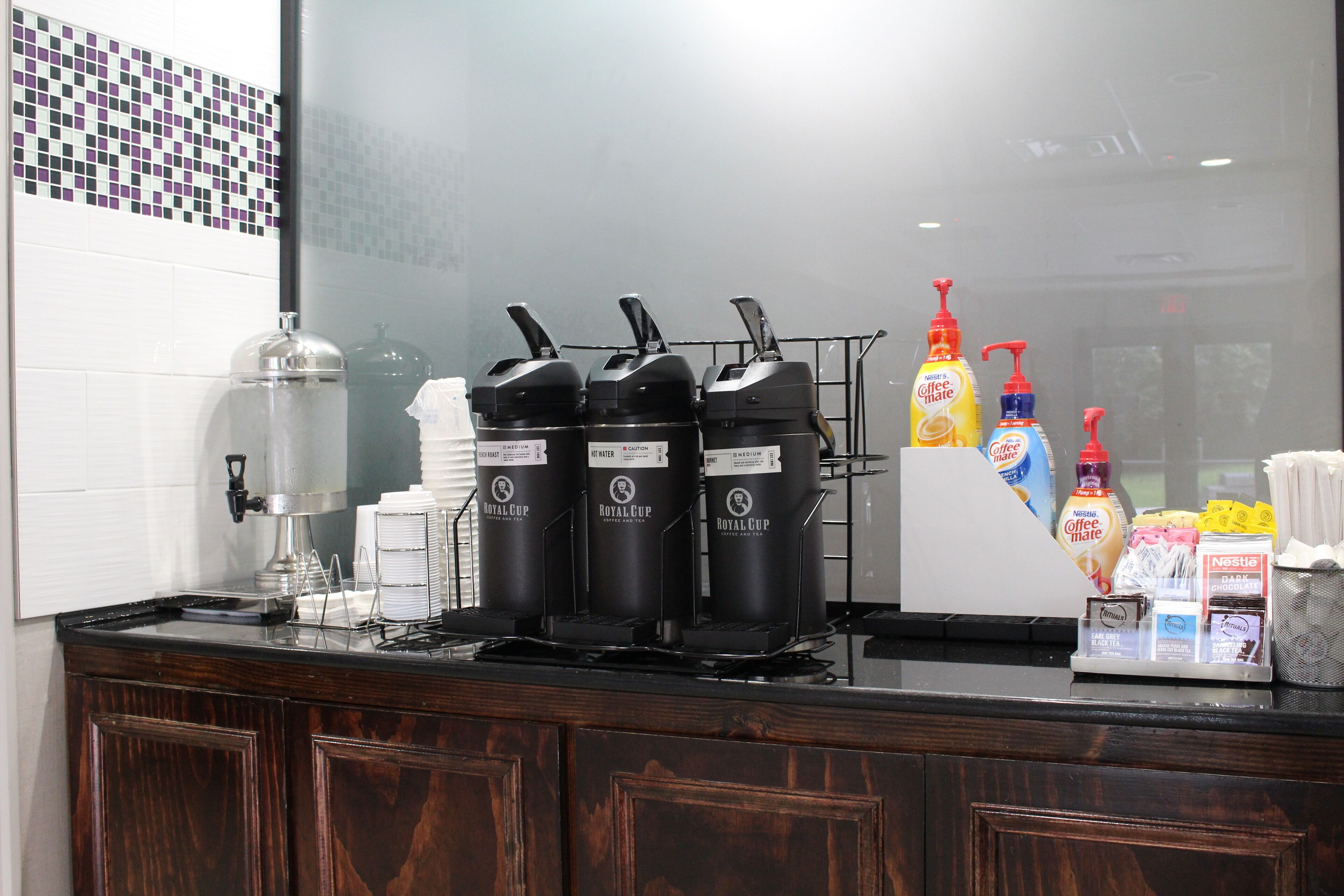 A coffee station with multiple Royal Cup coffee makers, a coffee machine, and various coffee and tea products.