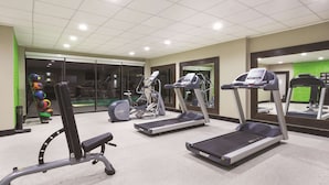 Une salle de sport équipée de tapis de course, d’un banc et de matériel d’exercice.