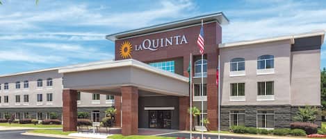 A hotel with a modern facade, a covered entrance, and a flagpole with the American flag.