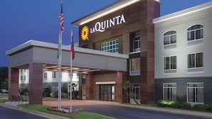 Un hôtel moderne, reconnaissable à son grand panneau « La Quinta », à son entrée couverte et à son mât portant le drapeau américain.
