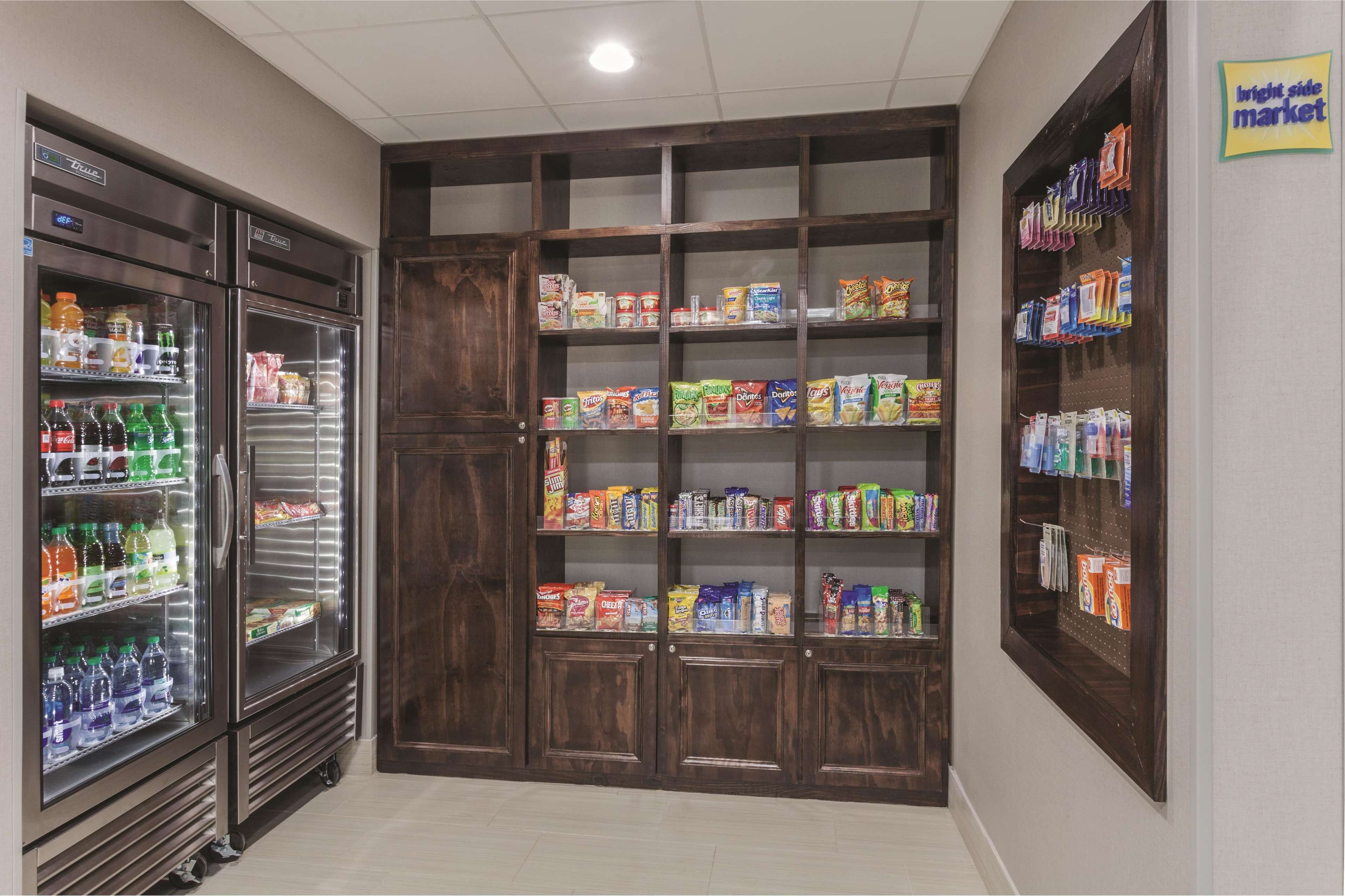Una tienda de comestibles con dispensadores refrigerados para bebidas, estantes llenos de bocadillos y un letrero para el mercado del lado claro.