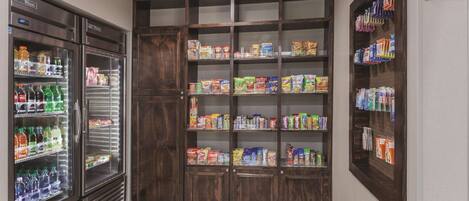 A grocery store with refrigerated beverage dispensers, shelves stocked with snacks, and a sign for the light side market.