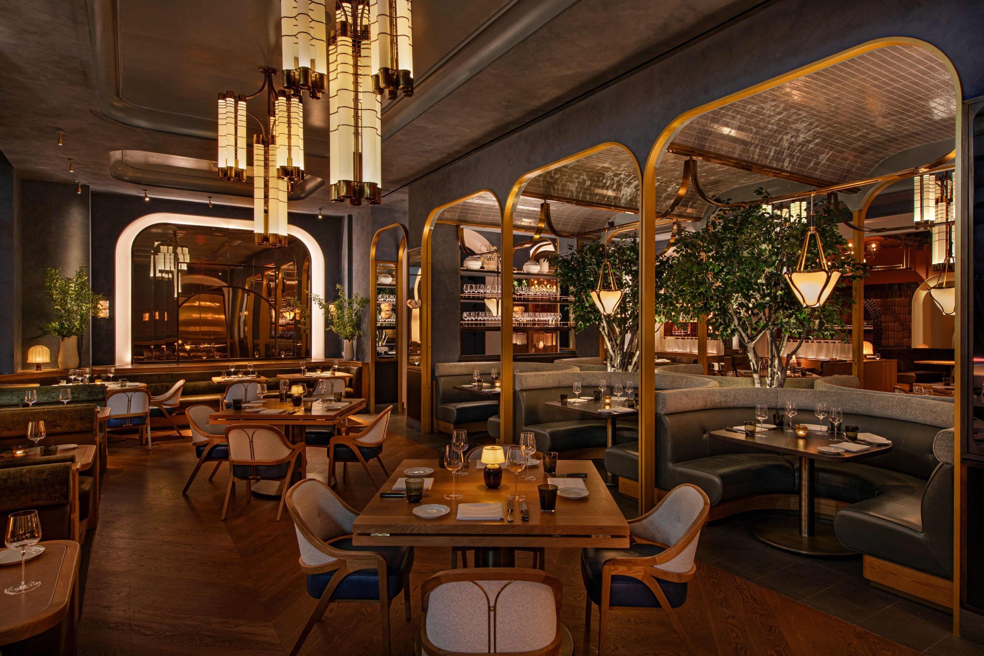 A modern restaurant interior with wooden tables, cushioned seating, and decorative lighting.