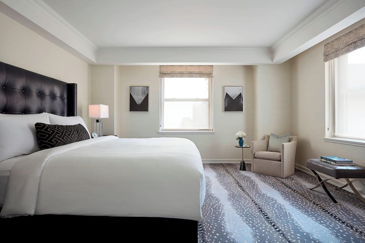 Habitación de hotel con una cama grande, una silla, una mesita y una ventana con vistas.