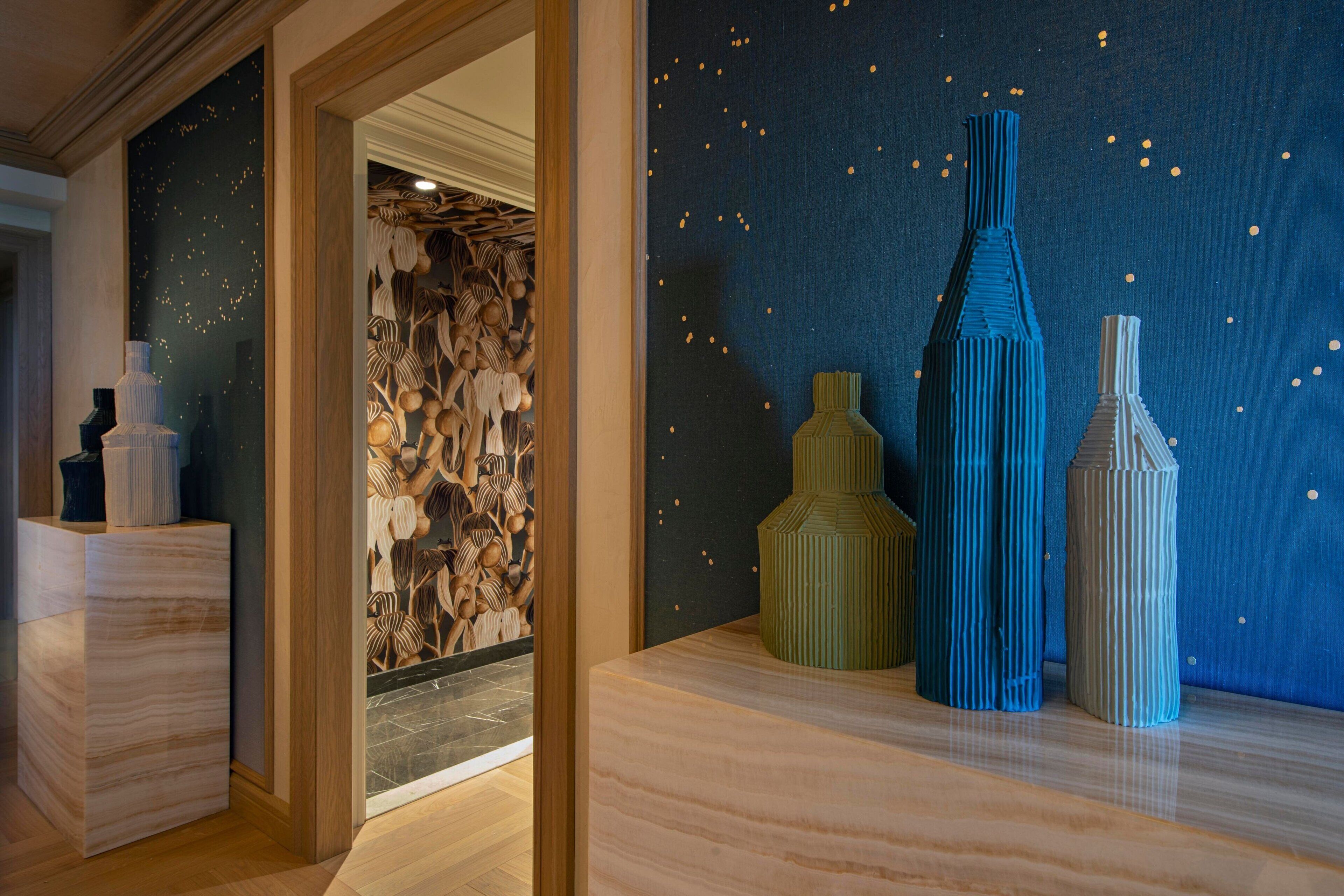 Una habitación con un mostrador de recepción de madera, una pared con diseño de estrellas y tres altos jarrones.