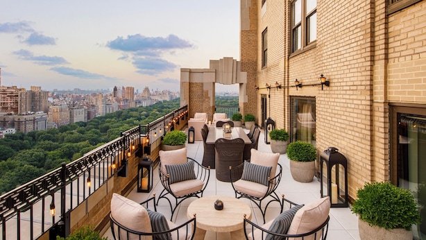 Una terraza en la azotea con mobiliario exterior, vistas a la ciudad y un edificio de ladrillo.