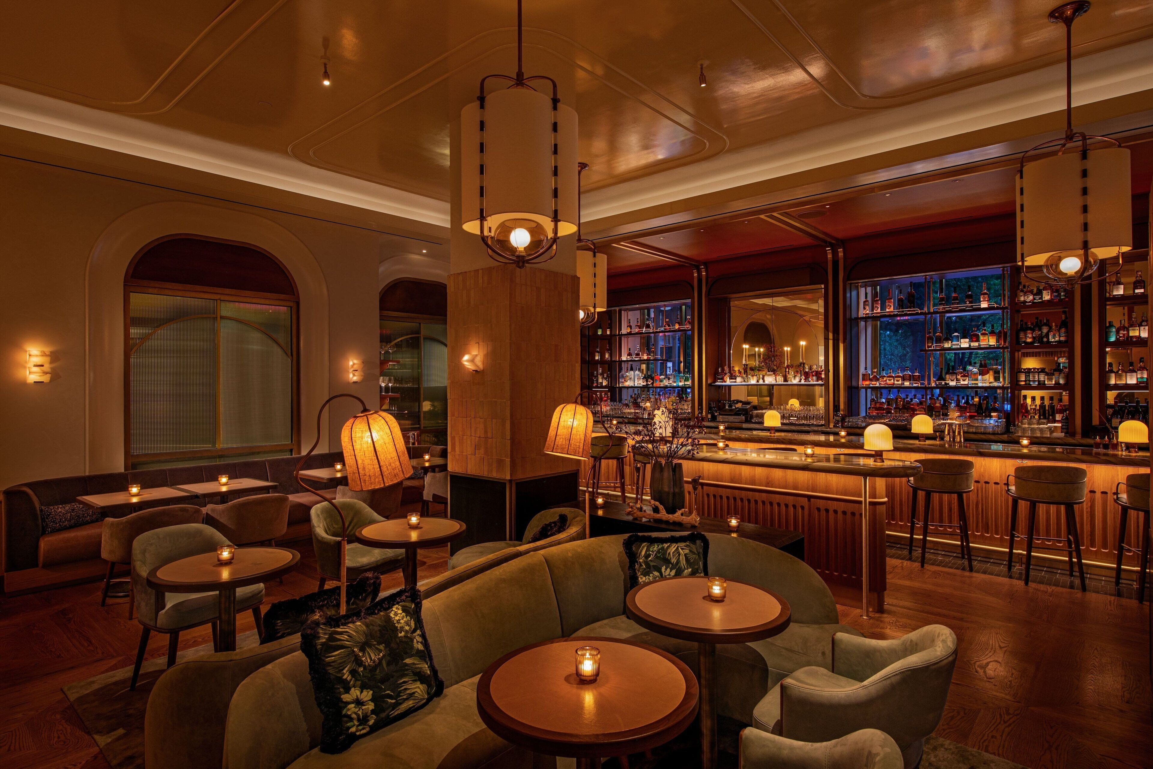 A bar area with round tables, bar stools, and a bar counter with shelves of bottles.