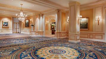 Un lobby espacioso con una alfombra grande y elaborada, candelabros y arquitectura clásica.