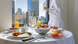 Una mesa de desayuno con diversos platos, una botella de champán y vista a la ciudad.