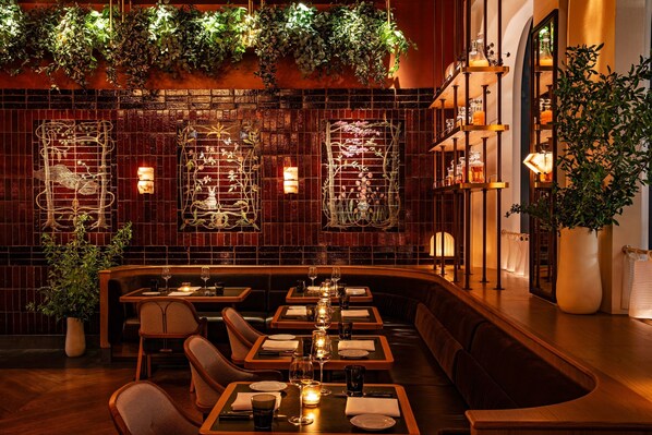 Un restaurante con mesas de madera, cabinas acolchadas y plantas colgantes.