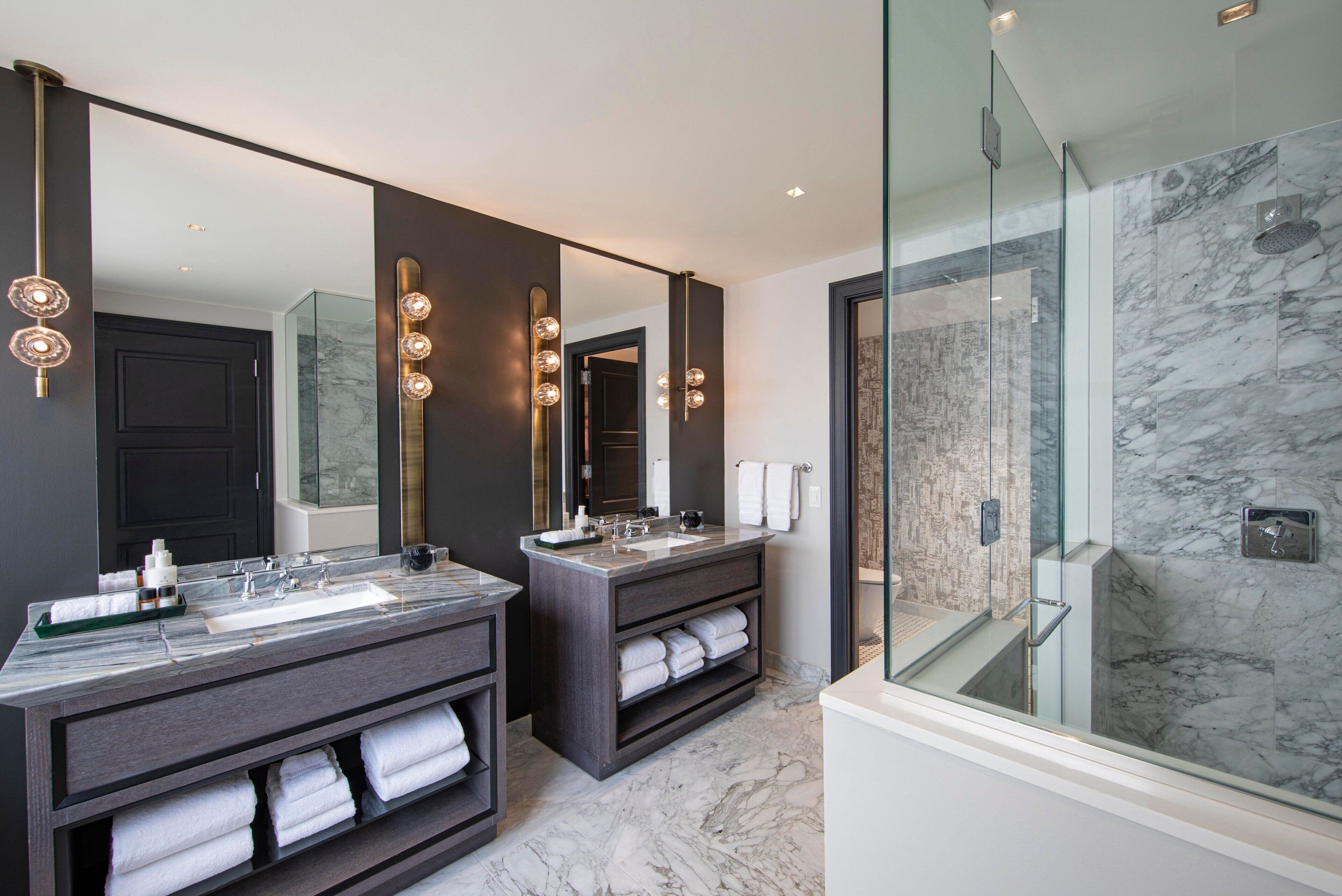 A modern bathroom with two sinks, large mirrors, and a glass-enclosed shower.