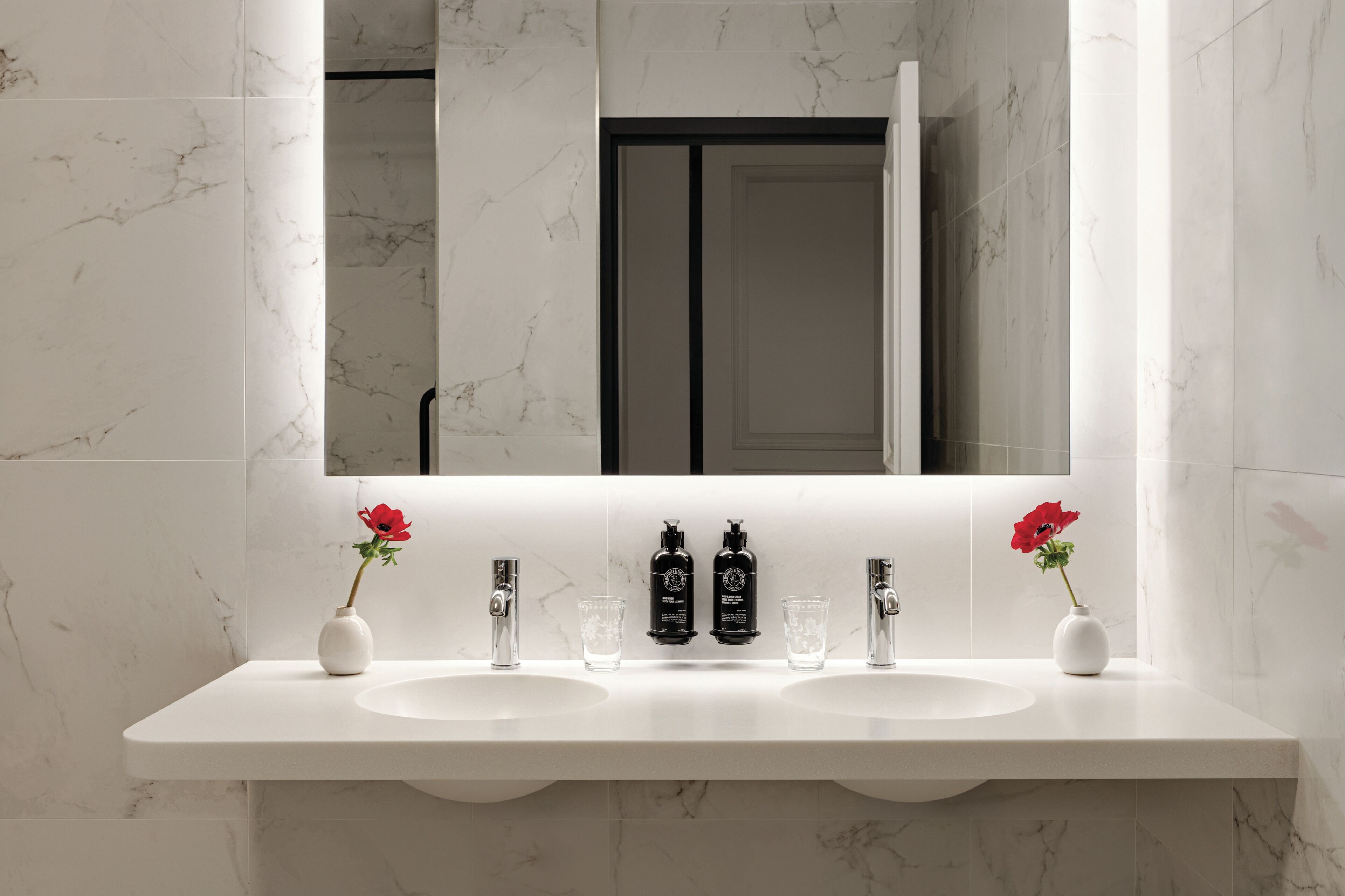 A bathroom with two sinks, a mirror, and a shower.