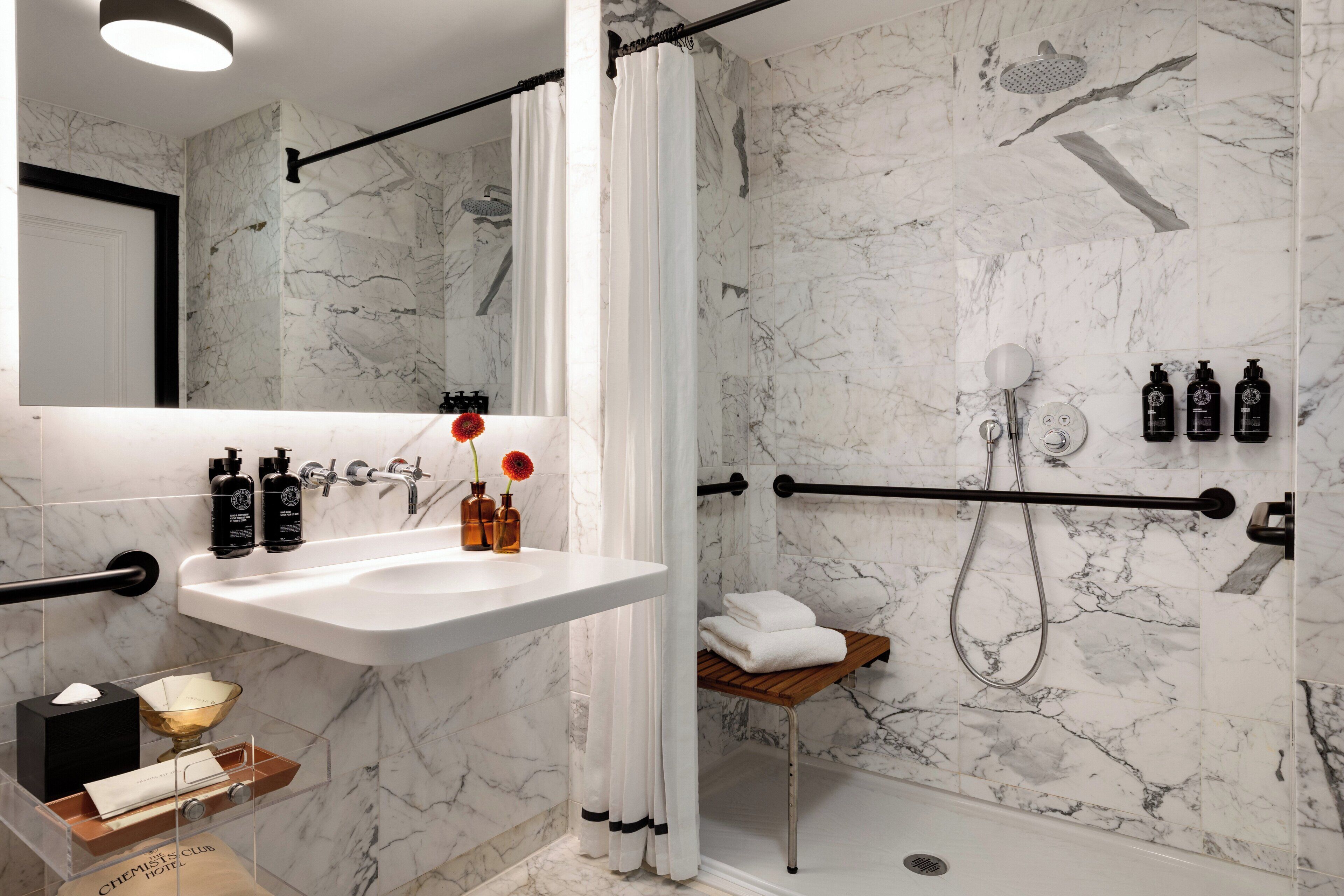 A modern bathroom with a marble shower, a white sink, and toiletries.