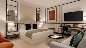 A hotel room with a large bed, a desk, a chair, a TV, and a sofa.