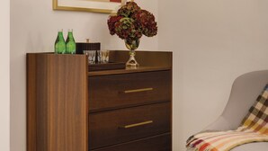 A room with a wooden dresser, a chair, a vase with flowers, and a framed abstract painting on the wall. - Eurostars The Chemists’ Club Hotel (New York)