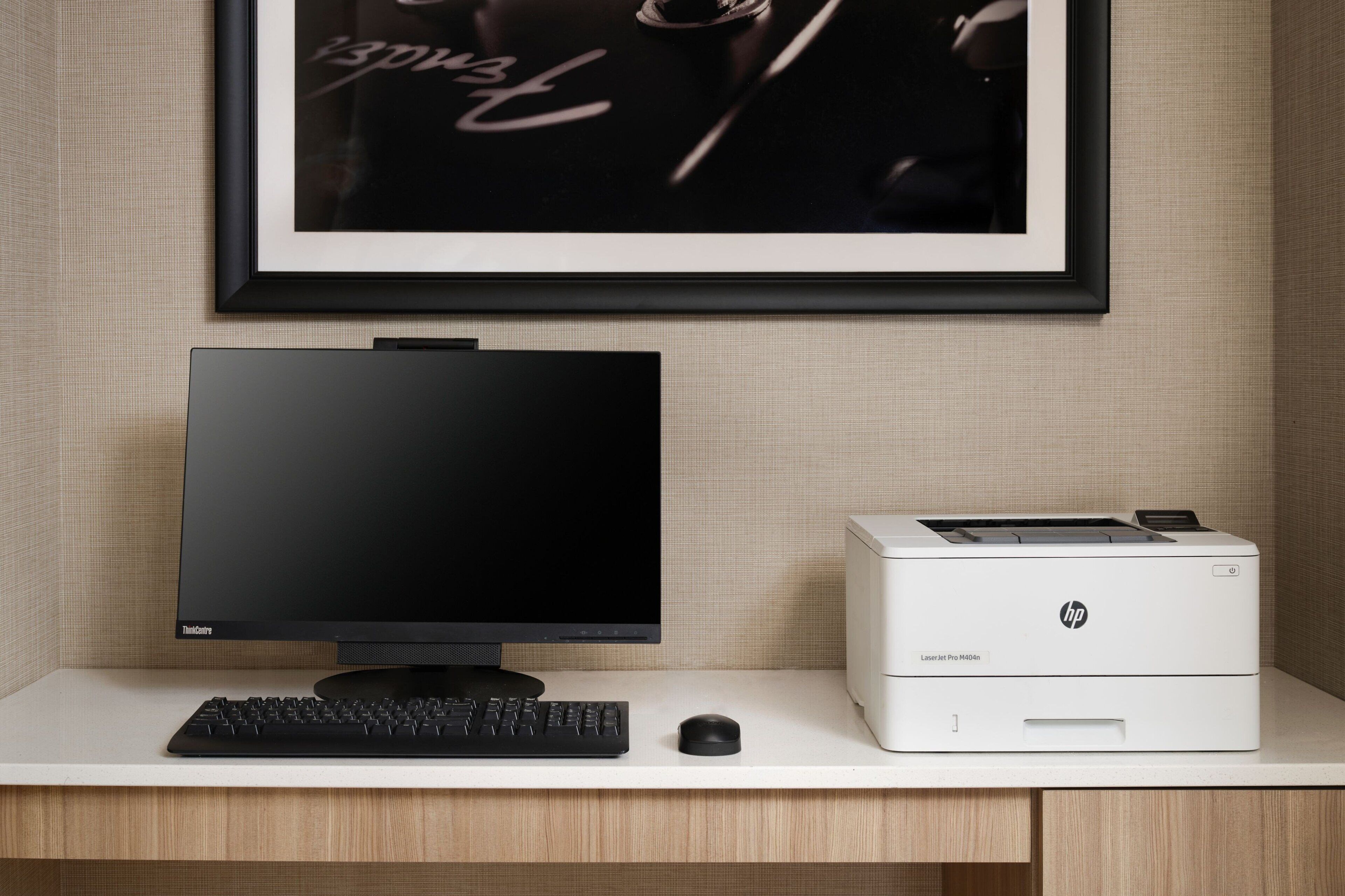 A modern office setup with a flat-screen monitor, a keyboard, and an HP laser printer on a white desk.