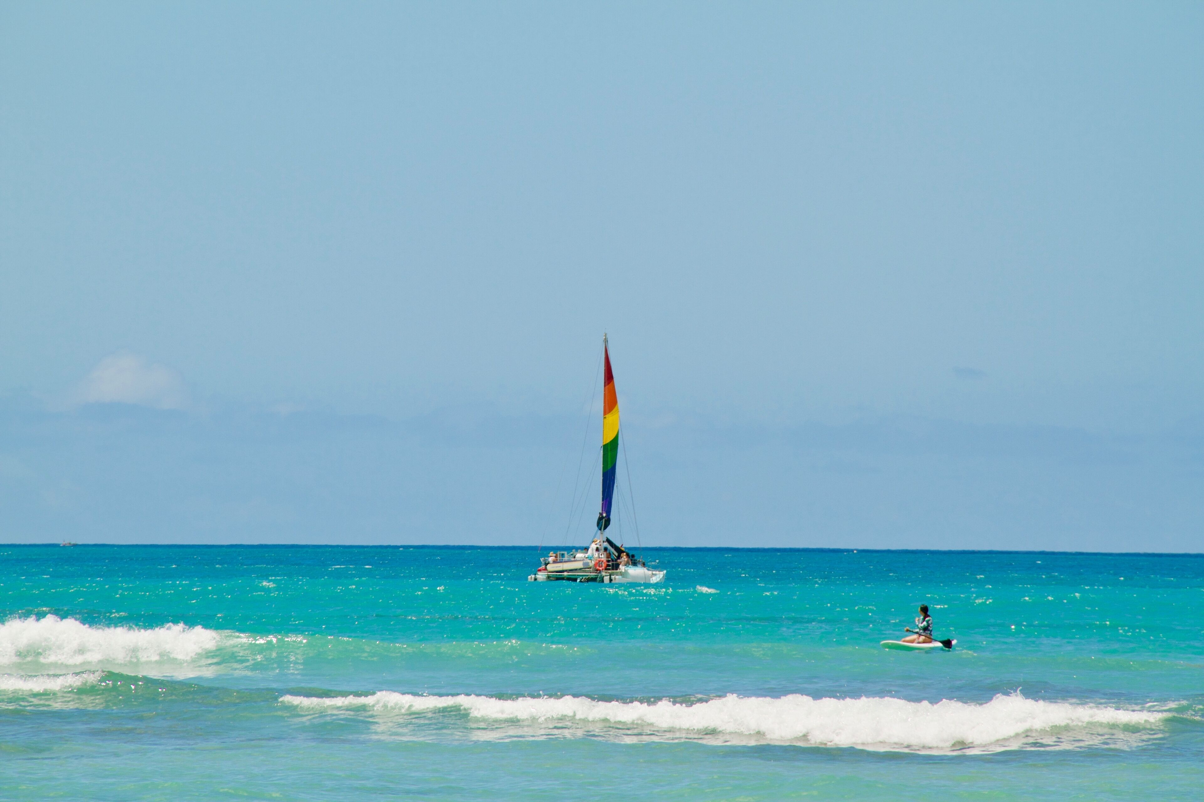 A sailboat with a colorful sail on the ocean.