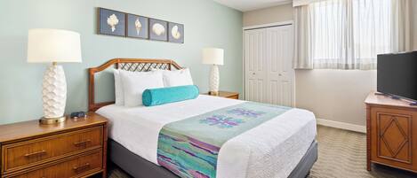 A hotel room with a bed, two bedside tables, a TV, a wardrobe, and a window with curtains.