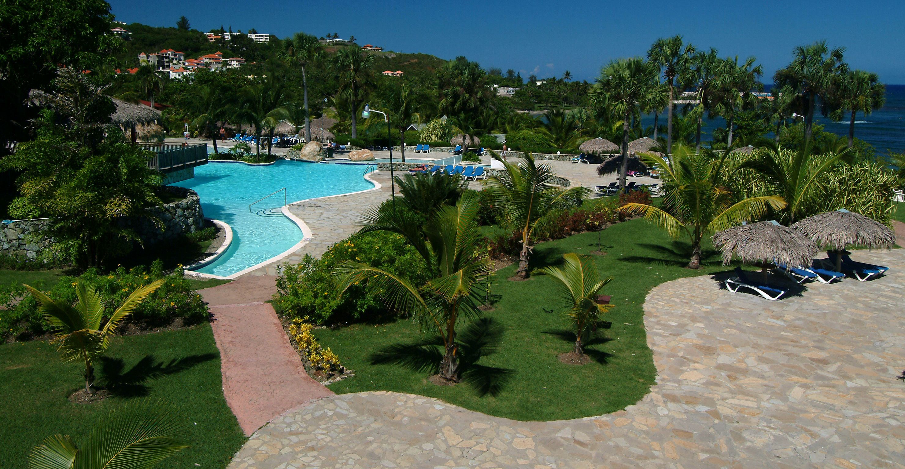A resort with a swimming pool, lounge chairs, and a view of the ocean.