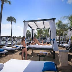 En la playa, arena blanca, sillas reclinables de playa, sombrillas