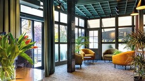 A spacious lobby with large windows, a high ceiling, and modern furniture.