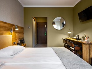 A hotel room with a bed, desk, chair, and a TV mounted on the wall. - Hotel Batory (Kraków)