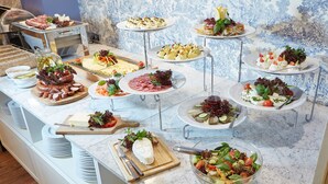 A buffet with various dishes including salads, cheeses, and meats.