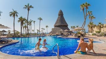 Relax by the pool surrounded by palm trees and lounge chairs.