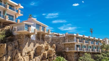 A hotel with multiple balconies, stone walls, and a clear blue sky.
