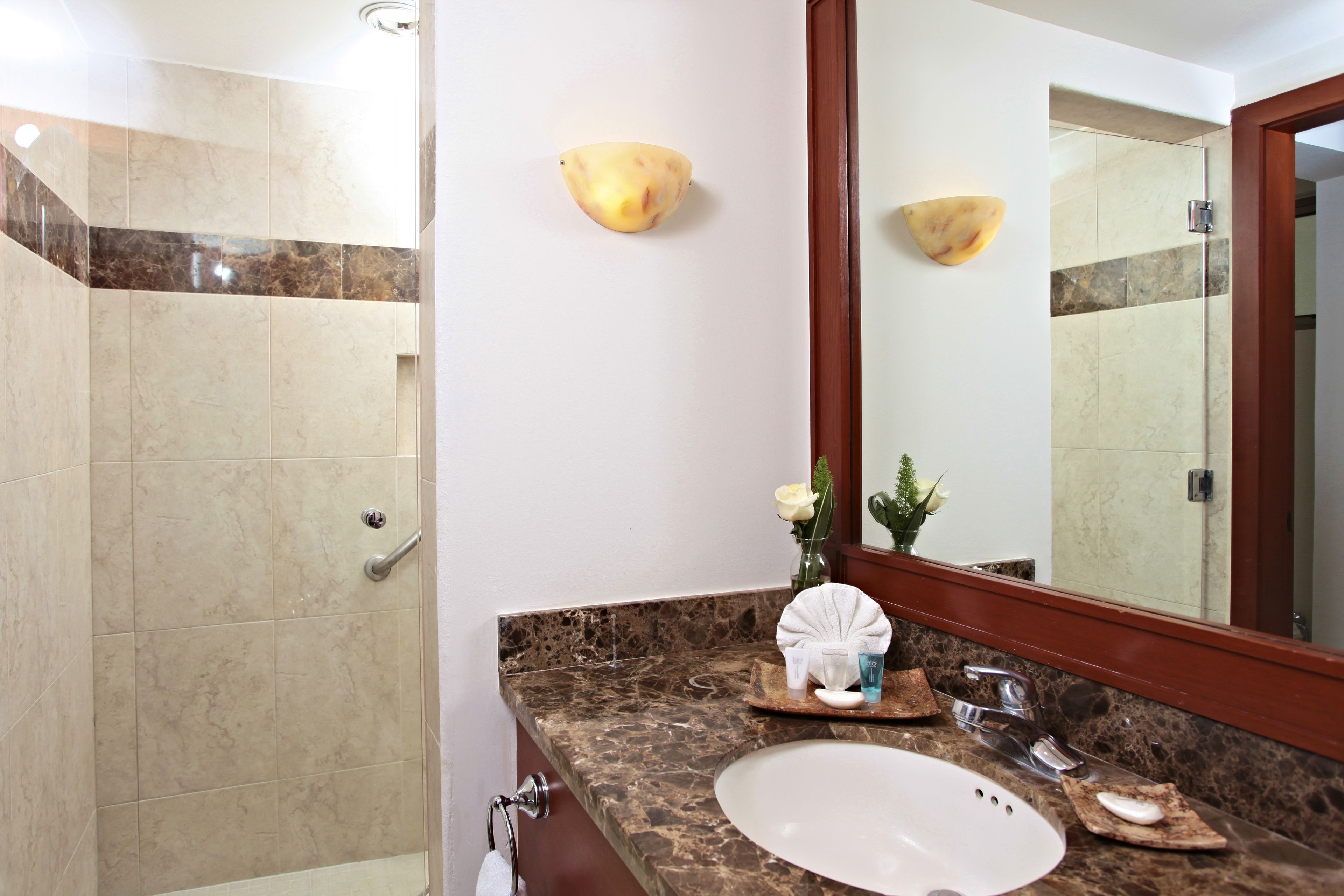 Ein Badezimmer mit Marmorwaschbecken, Spiegel, Dusche und Handtuchhalter.