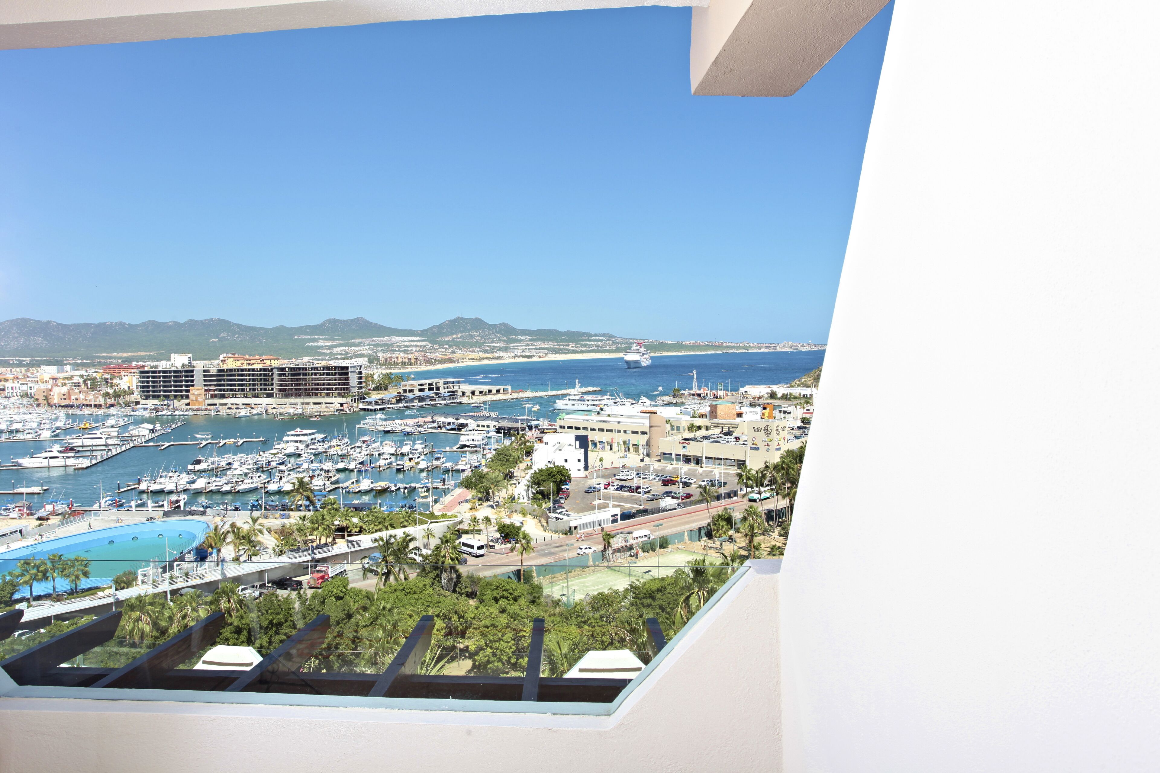 A marina with boats, a swimming pool, and a view of the city and mountains.