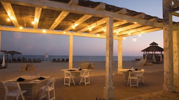 Un restaurante frente a la playa con terraza al aire libre, una cubierta de madera y vistas al océano.