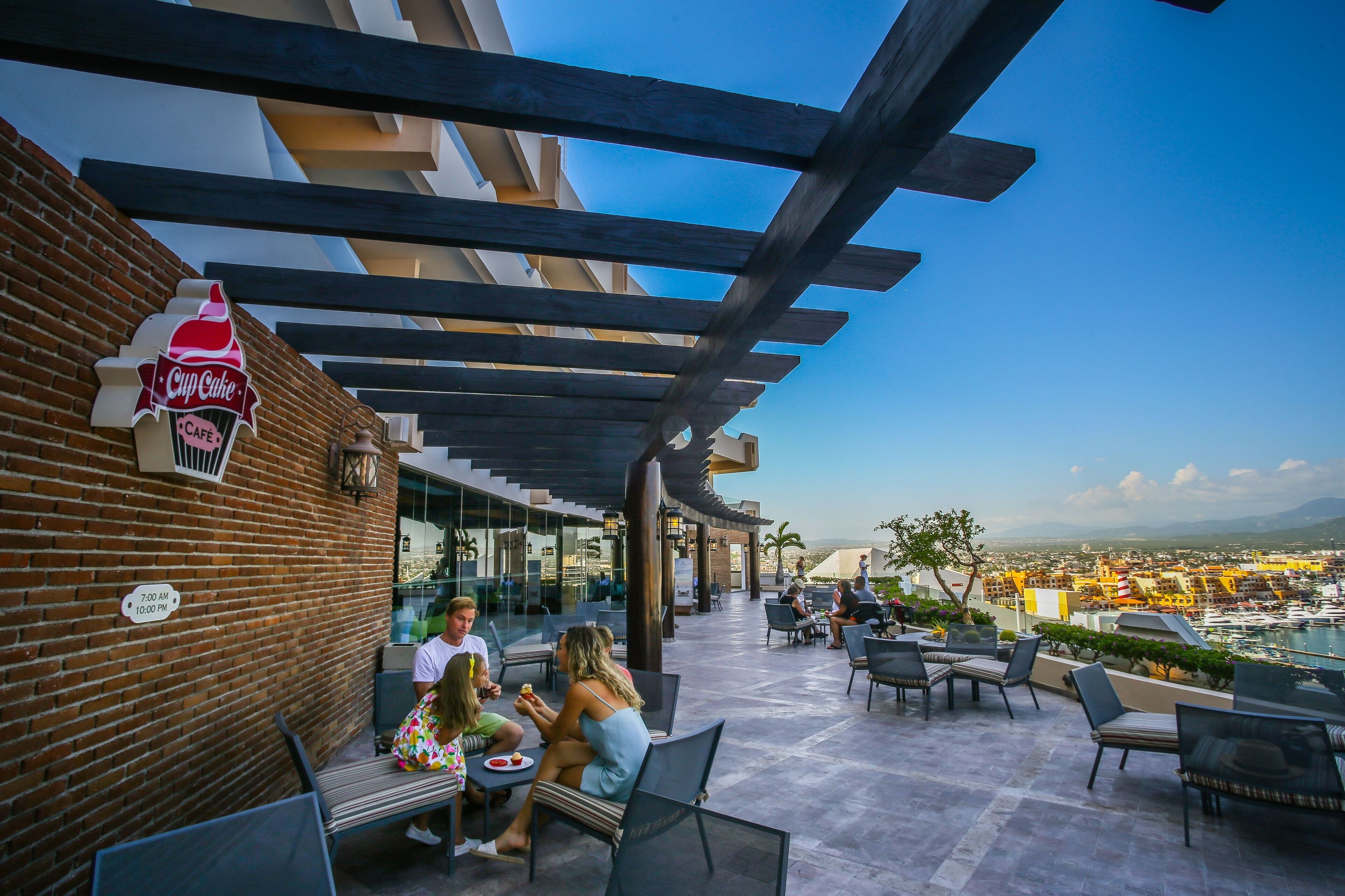 An outdoor café with a clear view of the city and a marina in the background.