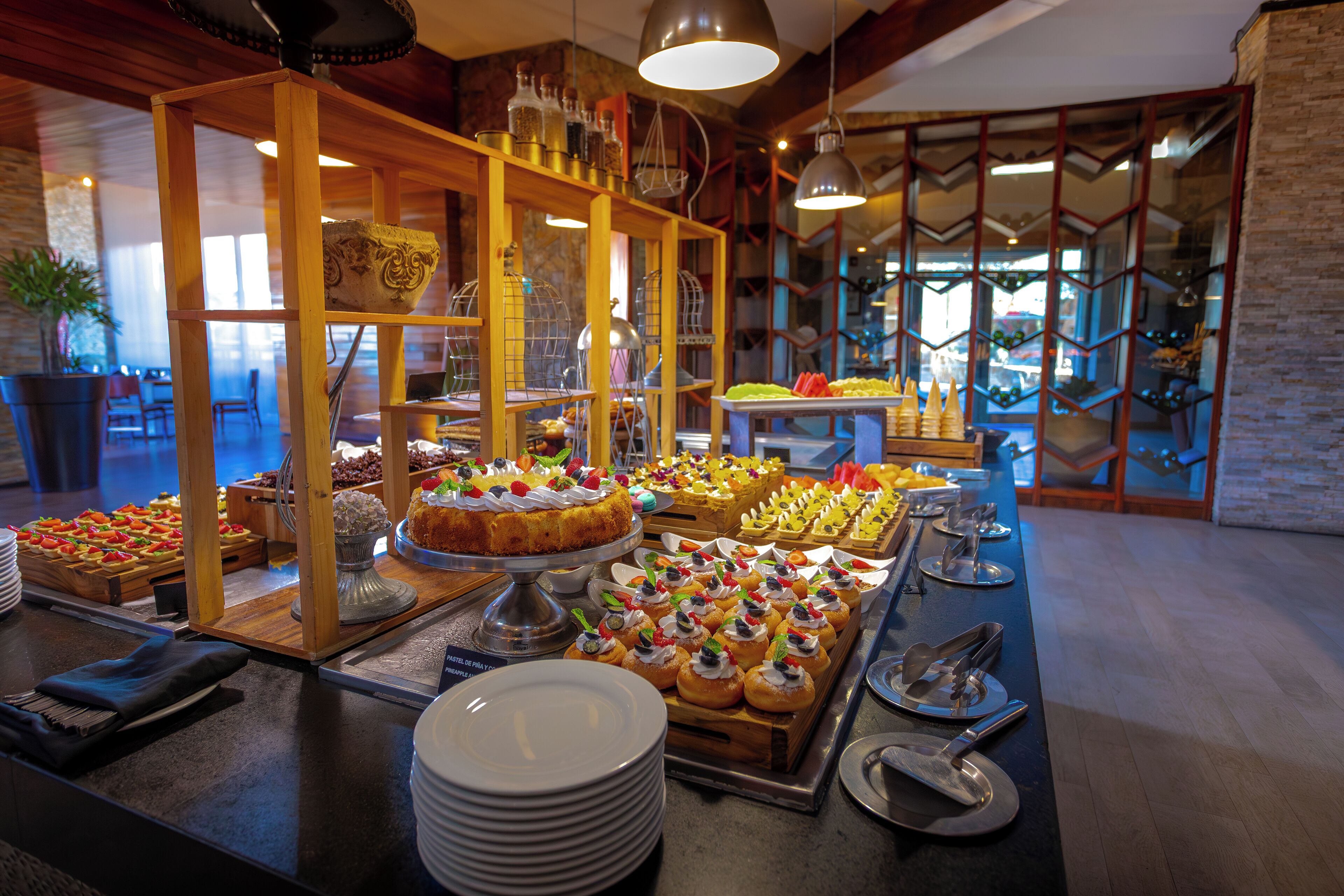 A buffet with various food items and a seating area with chairs and a table.
