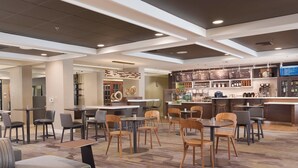 A modern hotel lobby with a bar area, seating arrangements, and a visible menu board.