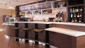 A modern bar area with a counter, stools, and a menu board.