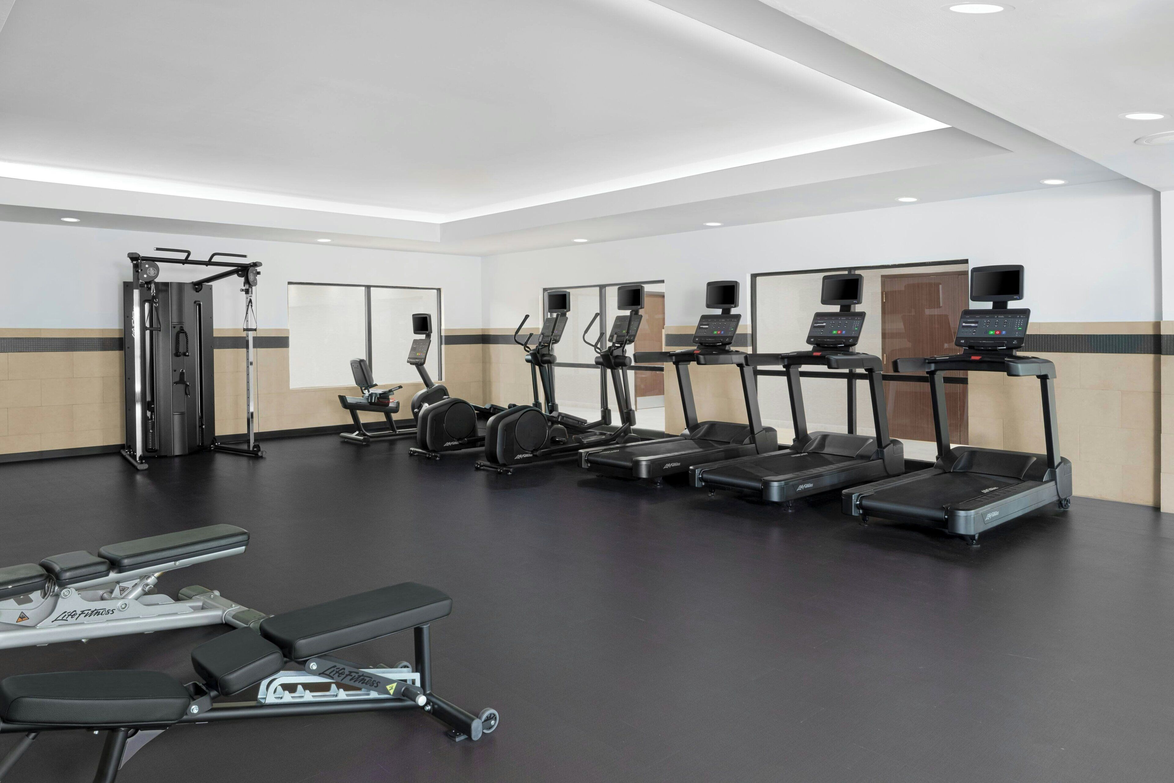 Een moderne sportschool met loopbanden, krachtapparaten en banken.