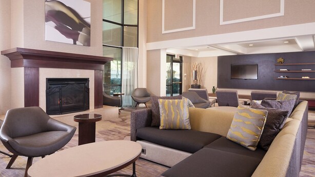 A modern lobby with a fireplace, comfortable seating, and a flat-screen TV.