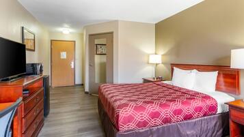 Una habitación de hotel con una cama, televisor, escritorio y cómoda.