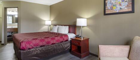 Una habitación de hotel con cama, mesita de noche, lámpara, silla y un mapa mural.