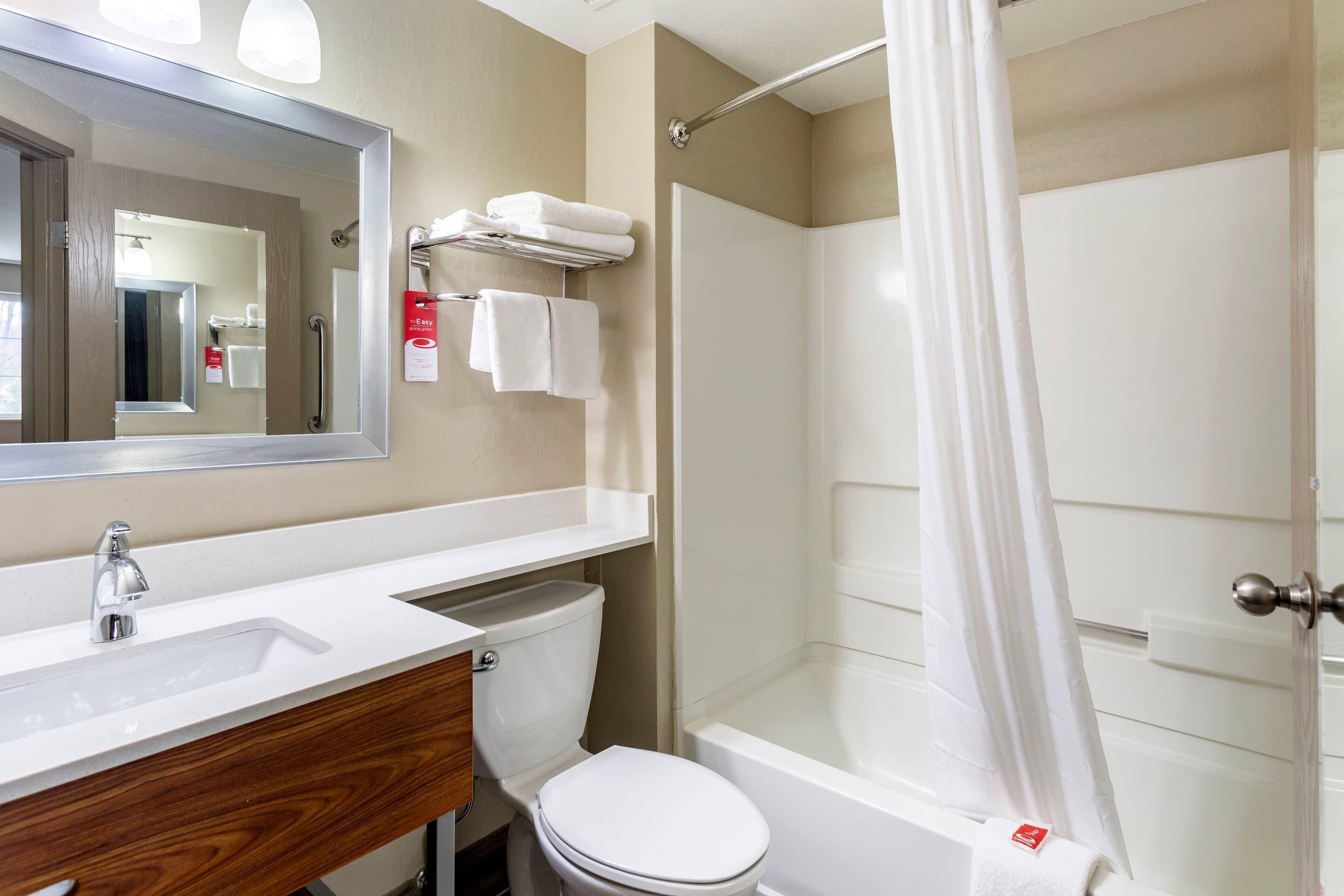 Ein Badezimmer mit Waschbecken, Spiegel, Toilette und Duschbereich.